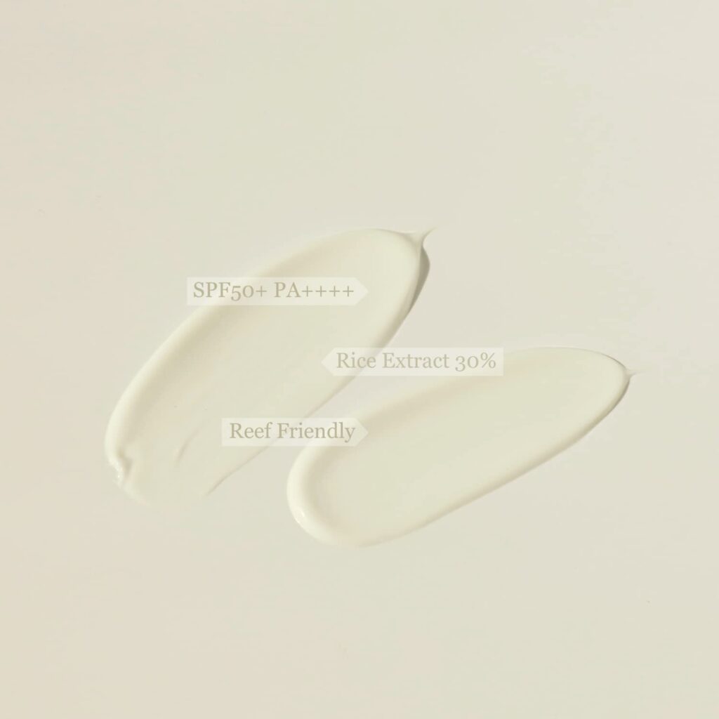 Two swatches of sunscreen on a plain background with text indicating “SPF50+ PA++++”, “Rice Extract 30%”, and “Reef Friendly”.