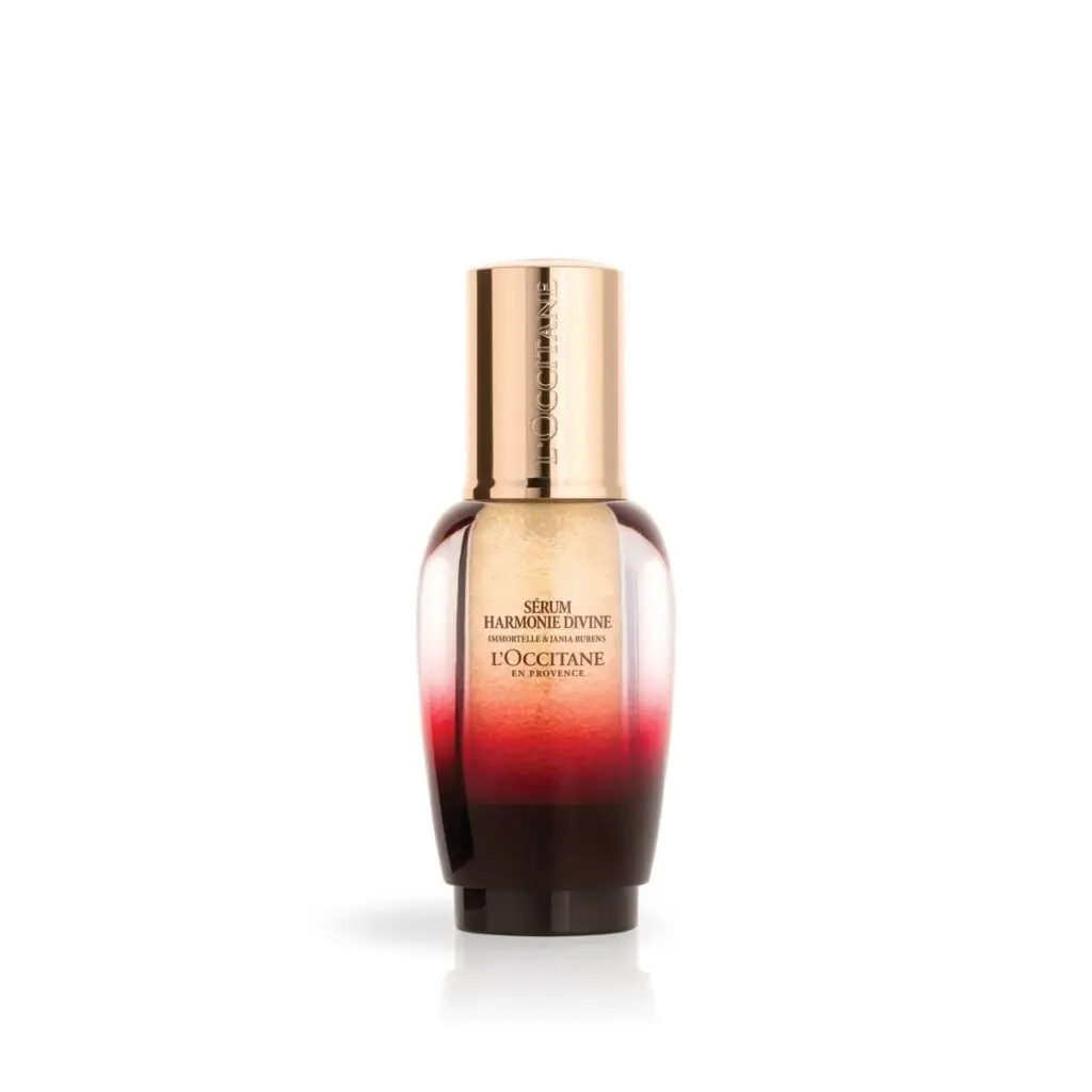 L’Occitane Serum Harmonie Divine in an ombre bottle with gold cap on a white background.