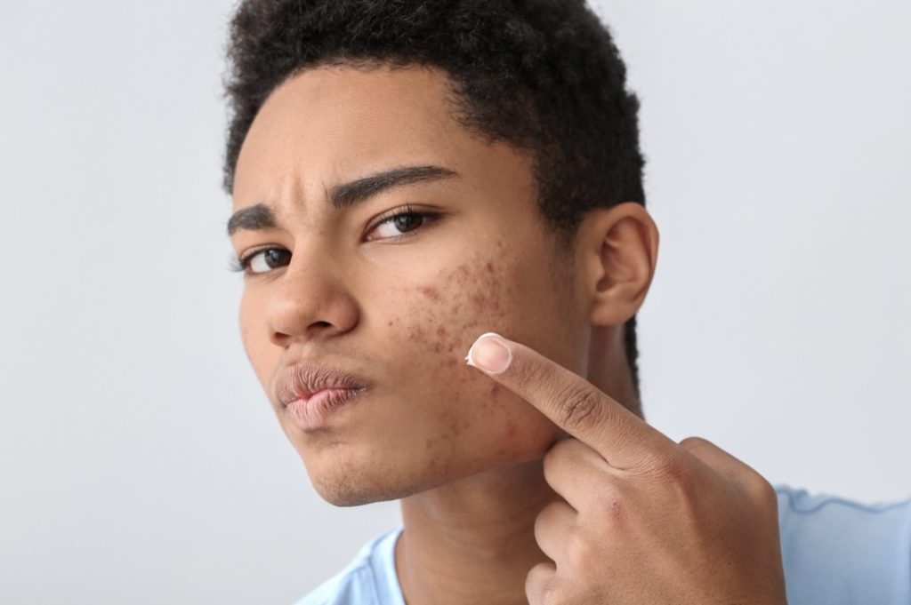 Image of a person pointing to their ear, with the face obscured for privacy.