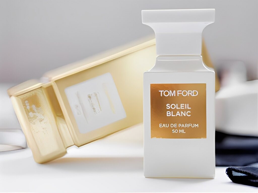 A bottle of Tom Ford Soleil Blanc Eau de Parfum in the foreground with a blurred background featuring additional bottles.