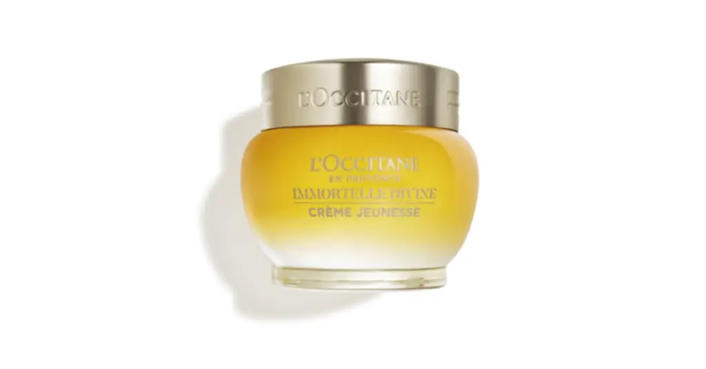 A white jar of L'Occitane Anti-Aging Immortelle Divine Cream with a gold lid, featuring the brand's logo and product.