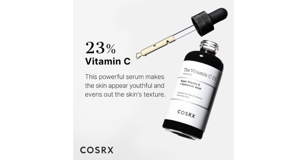 A dropper with a golden liquid is positioned above an open bottle labeled “The Vitamin C 23 Super Vitamin C Serum with Hyaluronic Acid” by COSRX. The background is a solid light color, and the text states “23% Vitamin C. This powerful serum makes the skin appear youthful and evens out the skin’s texture.”