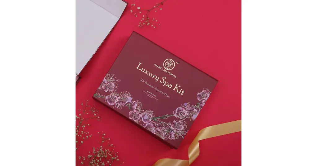 Luxury spa kit box on a red background with a gold ribbon and floral decorations.