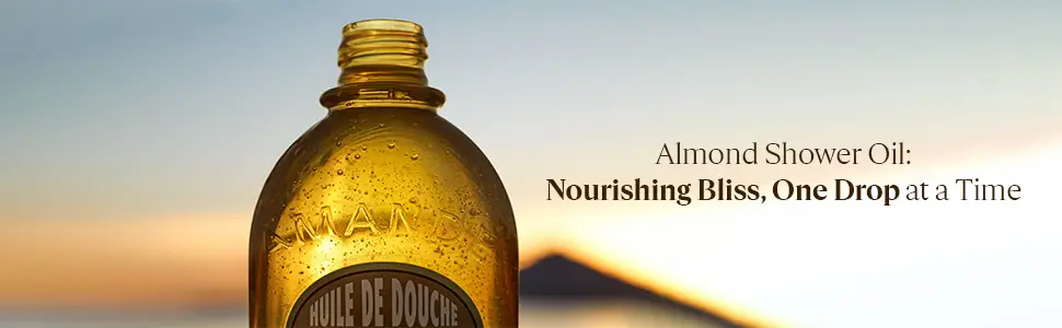 A transparent bottle of almond shower oil against a backdrop of a serene sunset with a mountain silhouette.