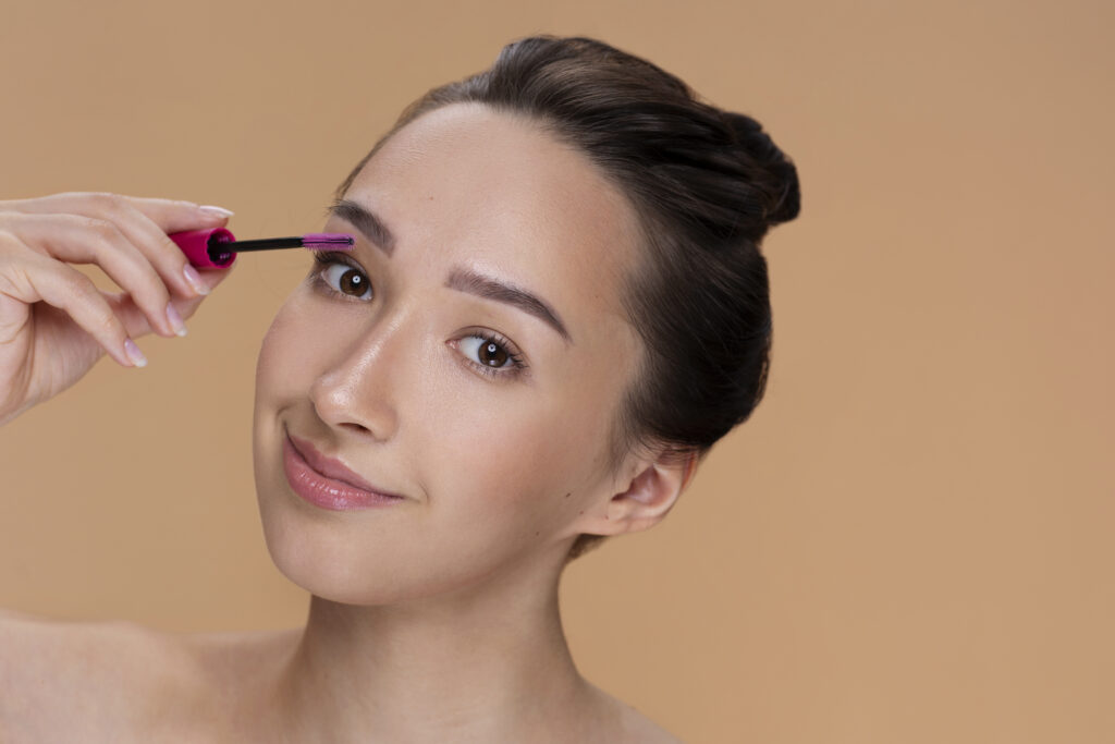 A person is holding a cosmetic product near their face, which is partially obscured by a blurred rectangle.